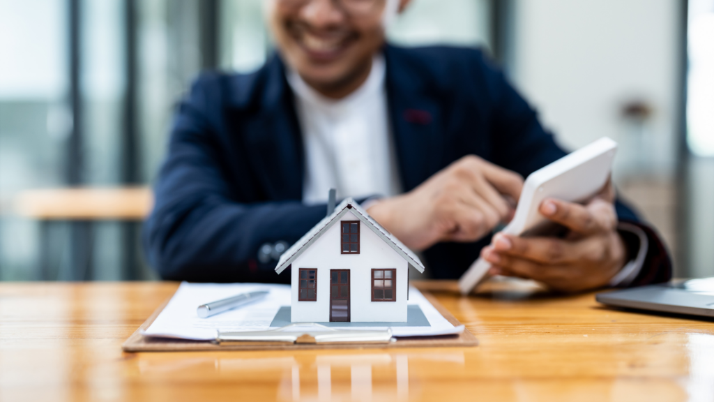 A photo focus in a model house and a mortgage agreement, with a moving truck and 'for sale' sign in the background, illustrating the concept of mortgage porting.